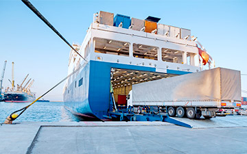 Semi-trailer truck driving onto a large cargo ship
