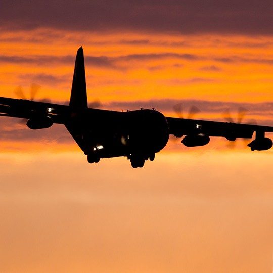 C-130 aircraft landing at sunset