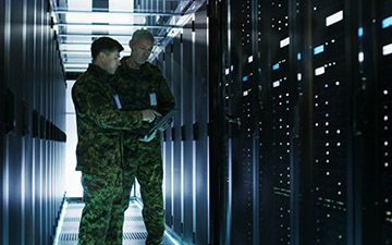 Two men dressed in army greens standing in a server room