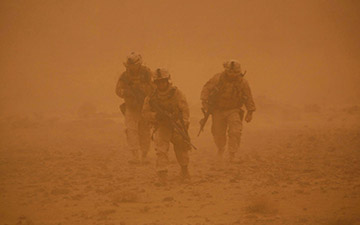 Three soldiers walking through a sand storm