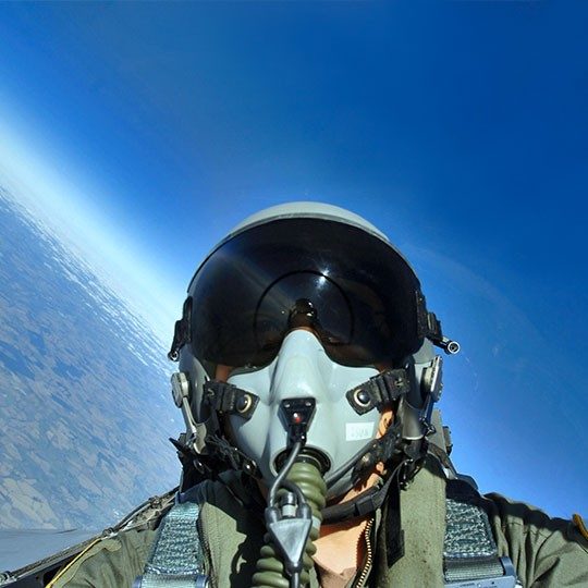Fighter pilot looking out window of jet